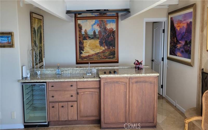 Family room with original paintings, wet bar with wine cooler, and 75