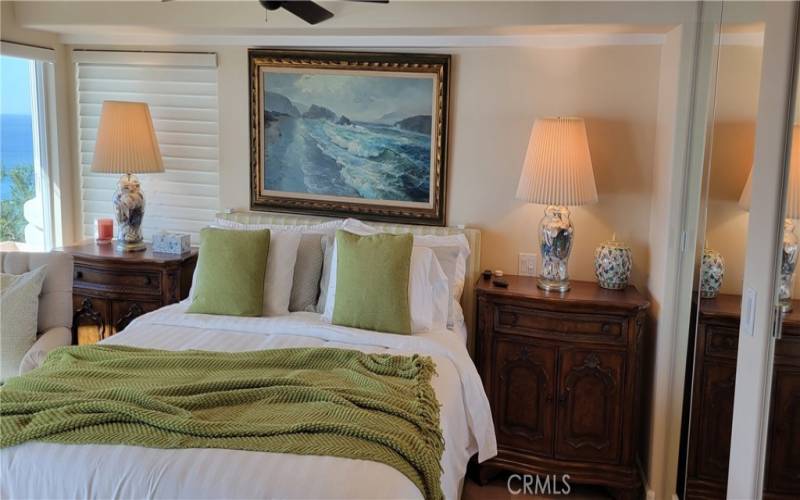 Primary ensuite king bedroom with blackout screens, ocean view deck and original painting.