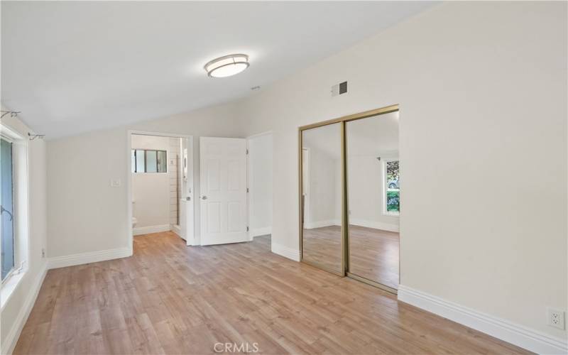 Bedroom view with bathroom and mirrored closet in background