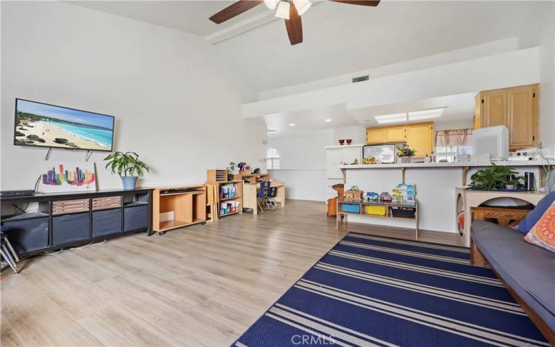 Oversized living room, open concept with kitchen and bar top on one end, and fireplace in the other.