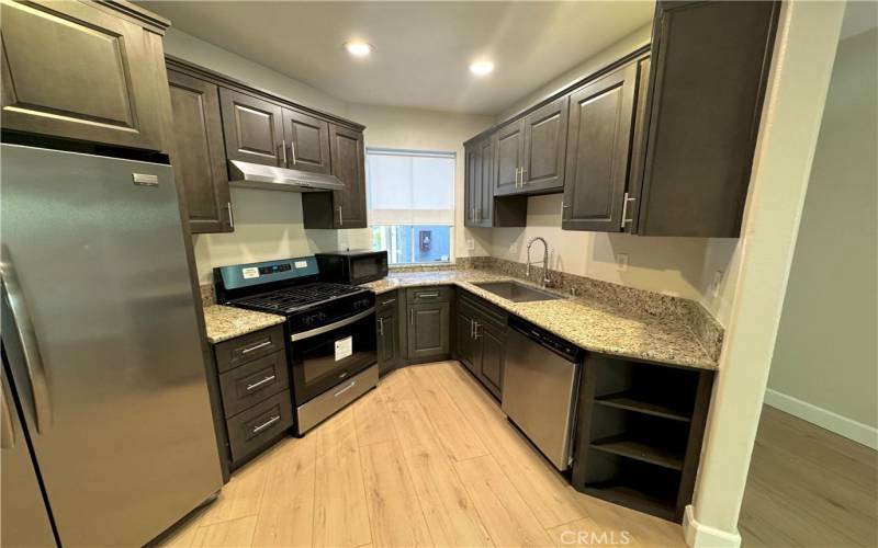 Remodeled kitchen with new stove and new floor and a fridge and new microwave.