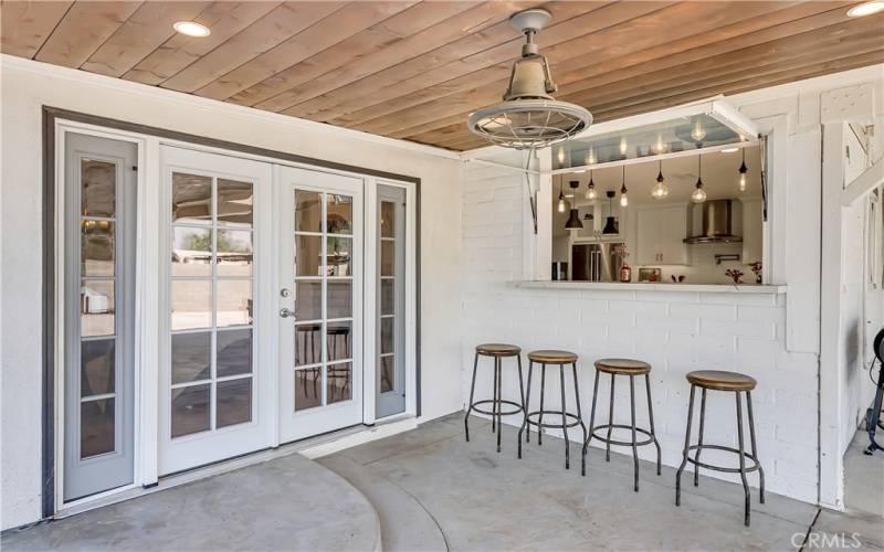 Third set of French doors from Living Room open up to the custom patio with pass-through window to the kitchen, and plumbing for an outdoor kitchen if you so desire.