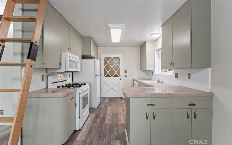 A ladder ascends to the loft nestled above the freshly painted kitchen.