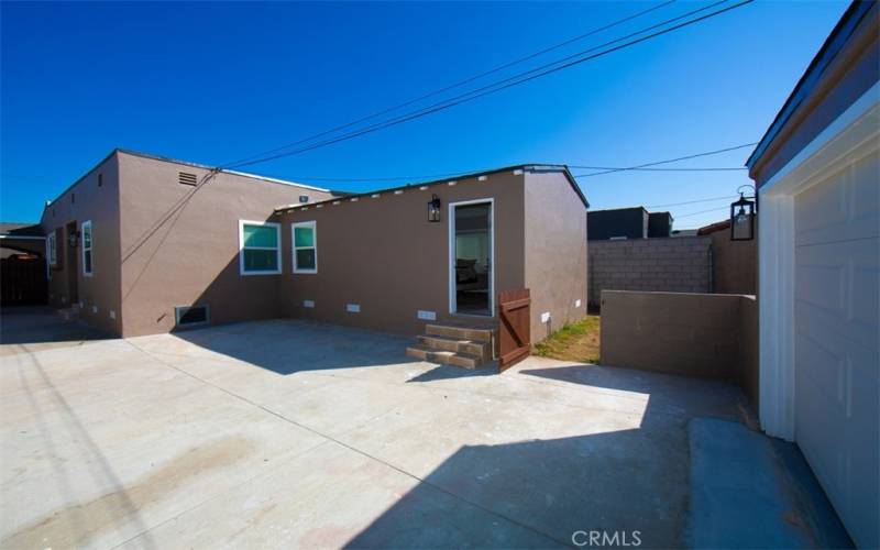 Large concrete backyard between house and garage