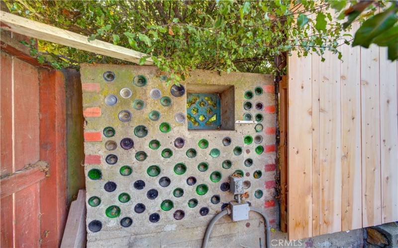 Artistic wine-bottle wall in backyard.