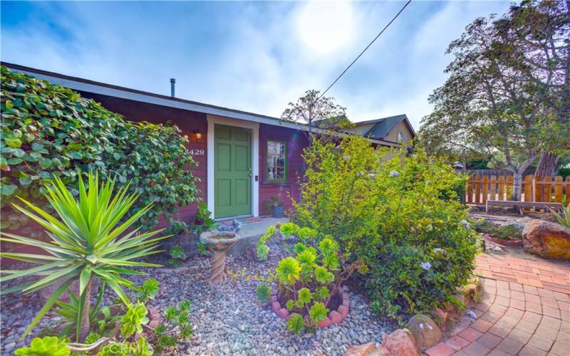 Landscaping featuring a variety of green plants are displayed in the front yard.