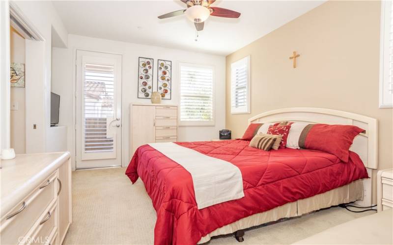 Master bedroom with plantation shutters, ceiling fan, and direct access to a large balcony