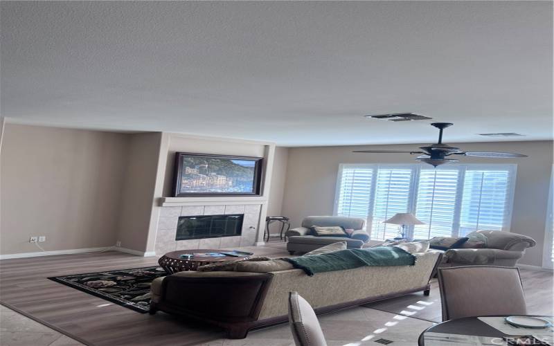 Open living room shared with Family room with earth tones and elegant window treatments.