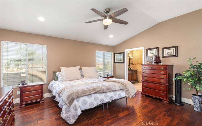 The spacious primary bedroom features rich hardwood flooring, vaulted ceilings, and tons of natural light