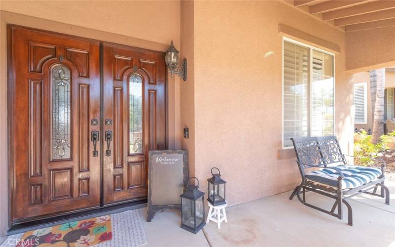 This inviting entry features elegant double doors, and a cozy seating area, creating a warm and welcoming first impression.