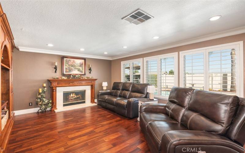 This bright family room features large windows, elegant hardwood floors, and a cozy fireplace, making it perfect for entertaining and relaxation.