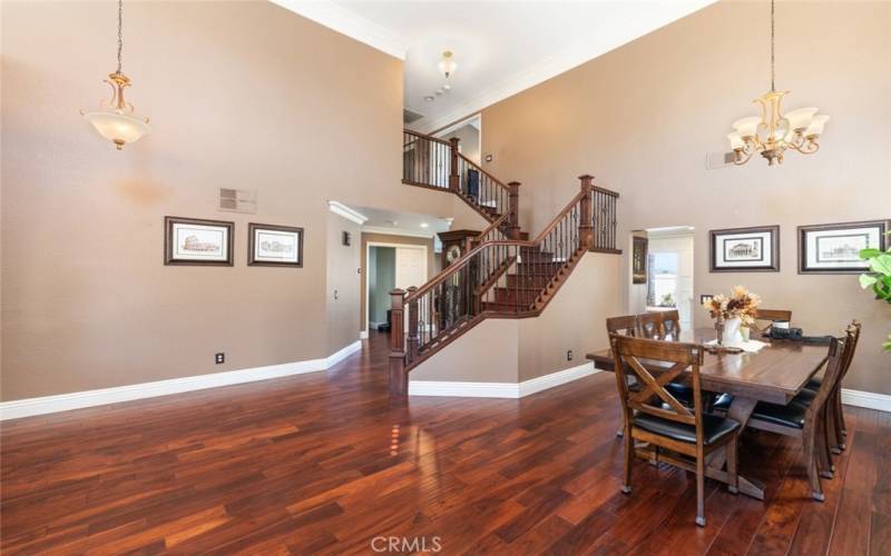 This elegant formal dining area features rich hardwood floors, high ceilings, and stylish wrought-iron staircase, perfect for hosting memorable gatherings.