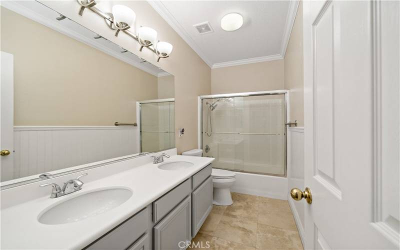 Hall bathroom with dual sinks and a combo shower/tub.