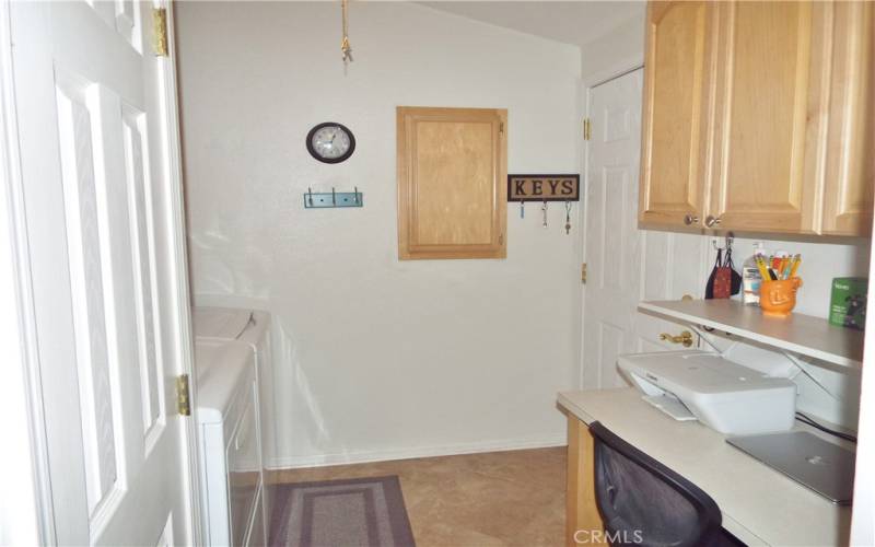 Big tile floor laundry that includes a desk/workstation, additional pantry and lots of cabinets.