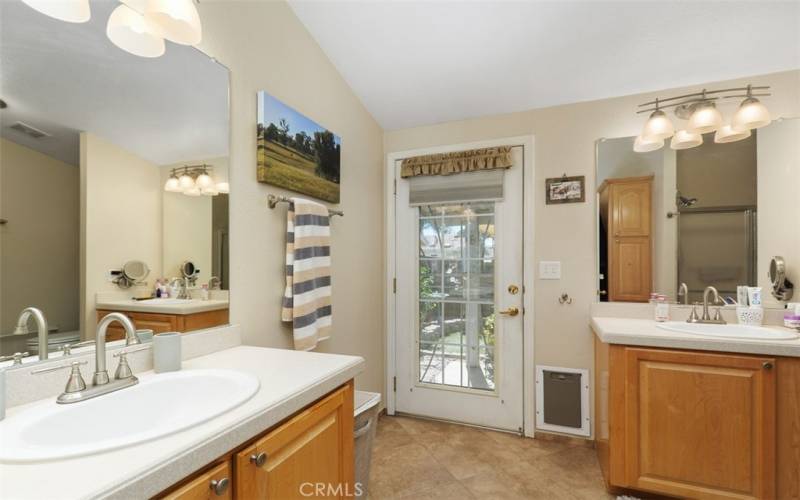 Dual vanity master bath featuring tile floors, shower and door to the covered patio.