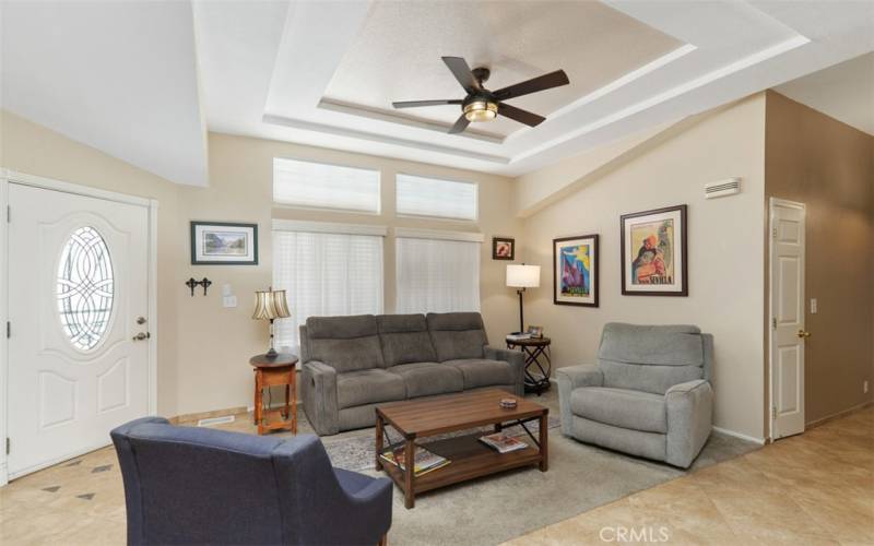 Elegant living room with tile floors and carpet insert, coffered ceiling and ceiling fan.