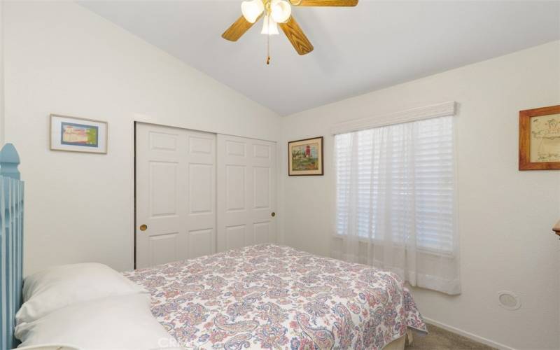 The carpeted guest bedroom with a ceiling fan.