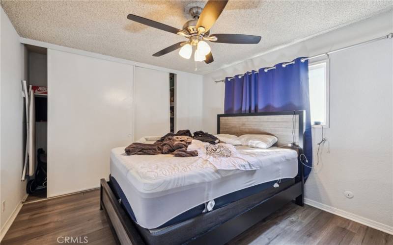 Bedroom with floor to ceiling closet space and modern fan.