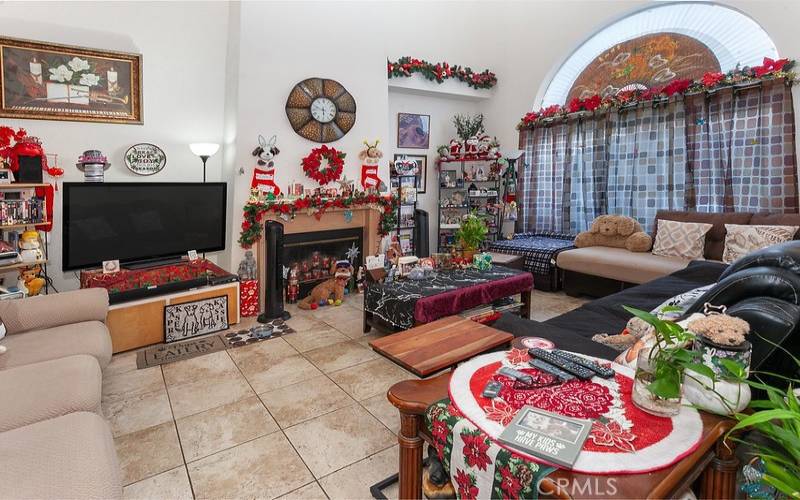 The family room is bathed in natural light from a multitude of windows, and is enhanced by soaring ceilings, fireplace with mantle and tiled floors.