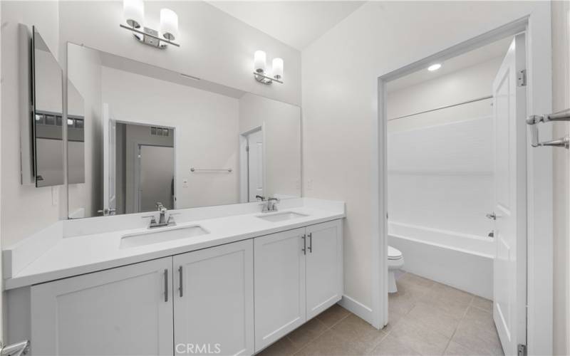 Shared hallway full bathroom with dual sinks.