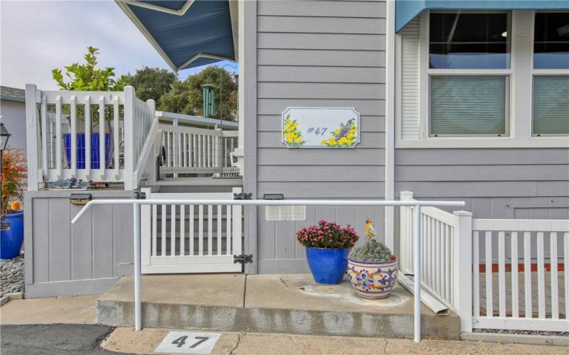 Front entry deck with vinyl fencing and colorful ceramic pots.