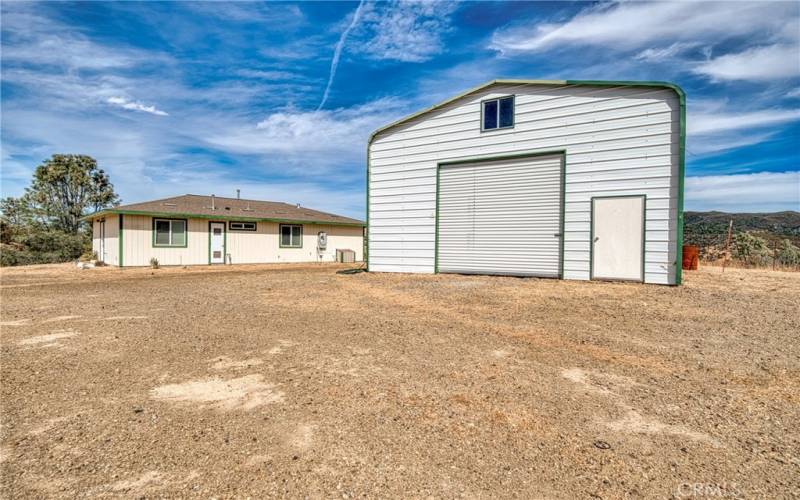 Large metal barn/shop/garage building with side door and a 10 foot rollup entrance.