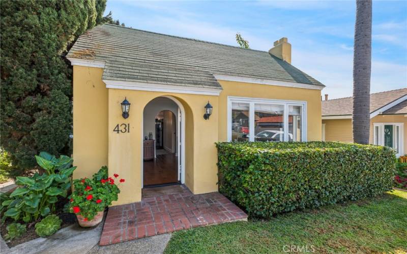 A beautifully manicured front yard and arched entry door create a welcoming introduction to the single-level, detached home, which greets friends and loved ones with a living room featuring a decorative fireplace and tray ceiling with crown molding.