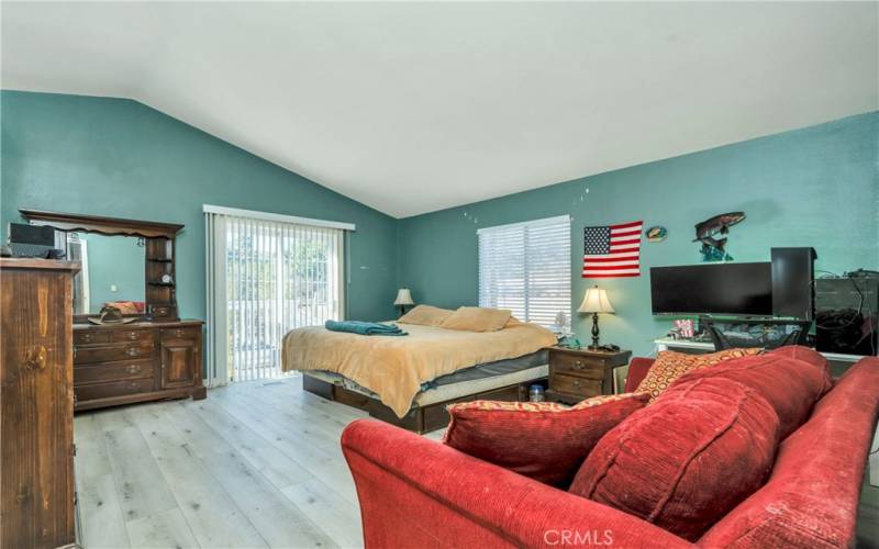 Primary bedroom with sitting area has sliding glass door to backyard.