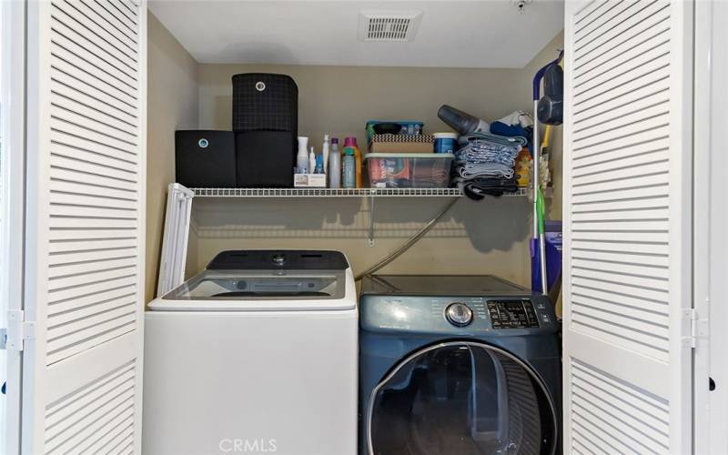 Washer and dryer in hall closet with extra storage shelving above