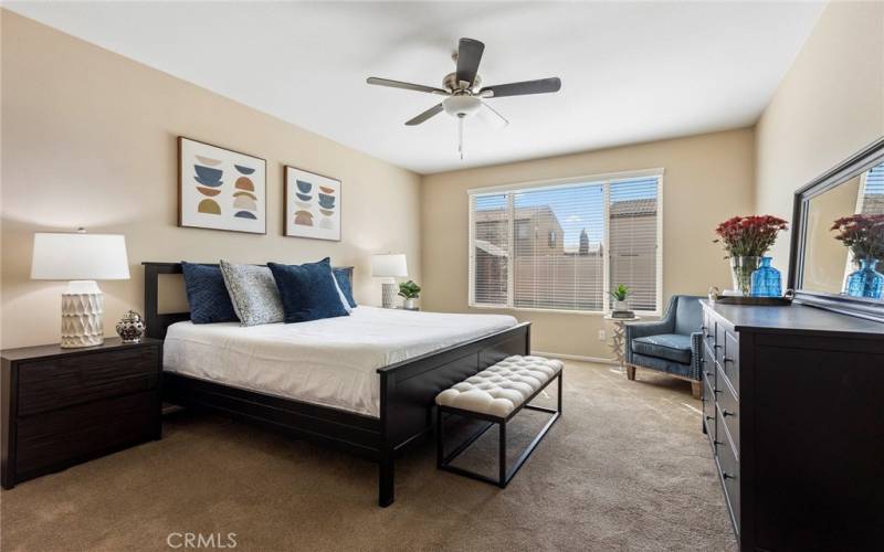 Primary bedroom with ceiling fan and backyard views