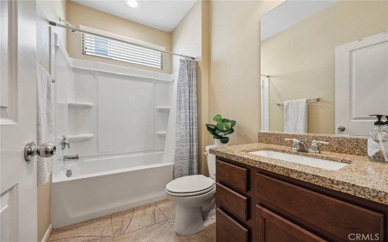 Hall bathroom with upgraded cabinetry and granite counters.