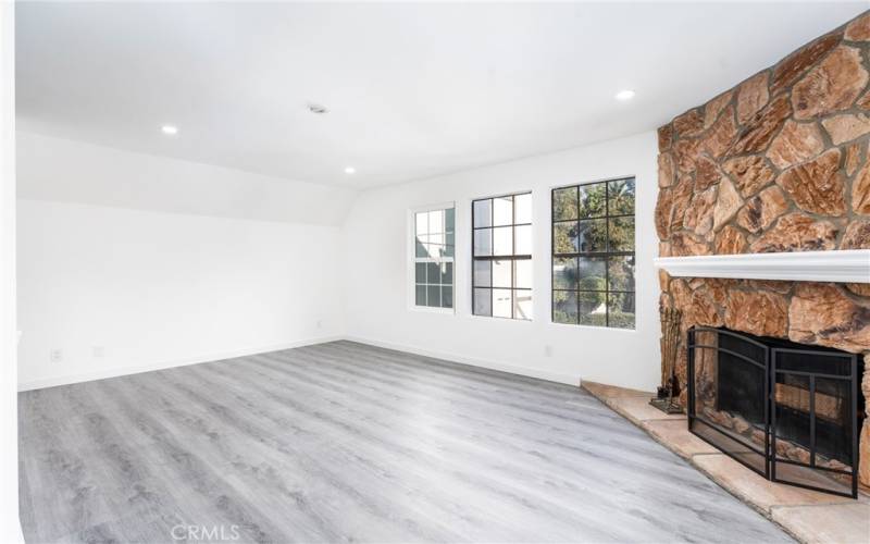 Living room with stone fireplace and modern floors.