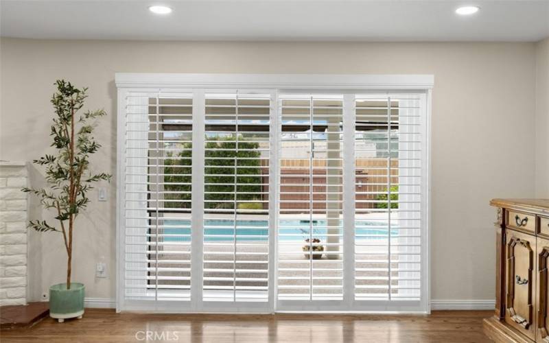 Living room with backyard pool view. Shutters cover sliding glass door.