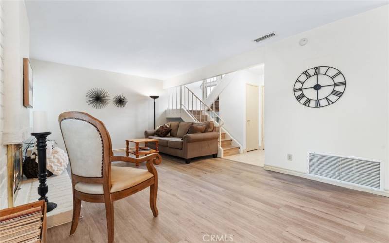 Another view of the spacious living room with wood laminate flooring with stairs also wood laminate.