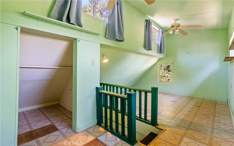 The loft is situated off the kitchen hallway by the bathroom. It features a vaulted ceiling with clearstory windows and ceiling fans.