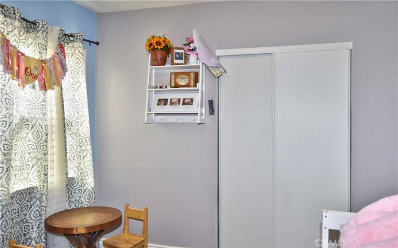 This darling 2nd bedroom offers more gorgeous wood laminate flooring, a modern ceiling fan, and views of the back patio.