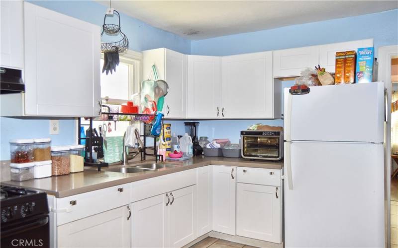 This attractive kitchen was fully remodeled in 2018 with porcelain tile flooring, modern Shaker-style cabinetry, quartz countertops, gas range, range hood, pull-out faucet, stainless steel double sinks and recessed lighting.