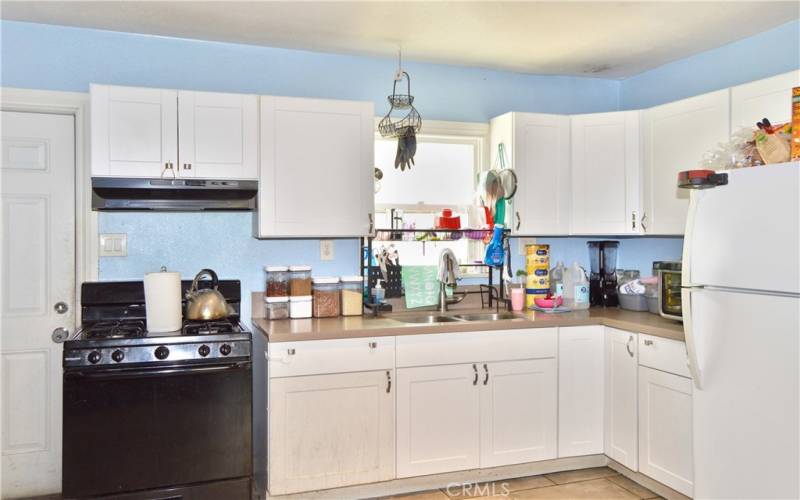 This attractive kitchen was fully remodeled in 2018 with porcelain tile flooring, modern Shaker-style cabinetry, quartz countertops, gas range, range hood, pull-out faucet, stainless steel double sinks and recessed lighting.