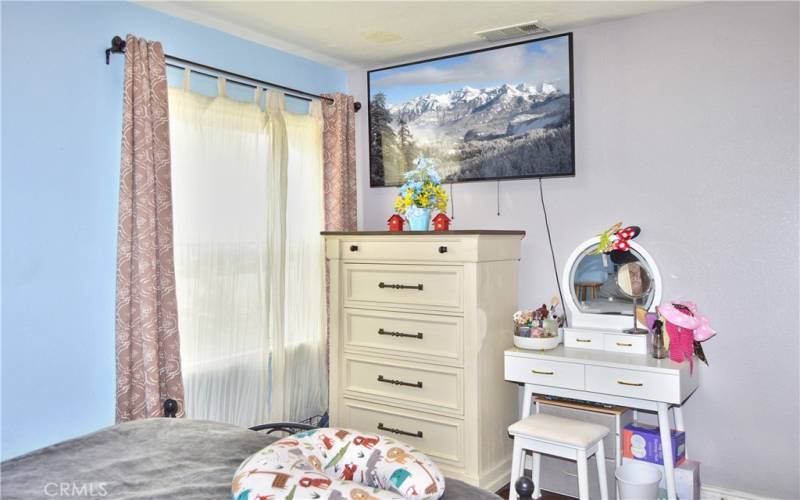 The primary bedroom looks out on the front yard and features more of that gorgeous wood laminate flooring and a modern ceiling fan light.