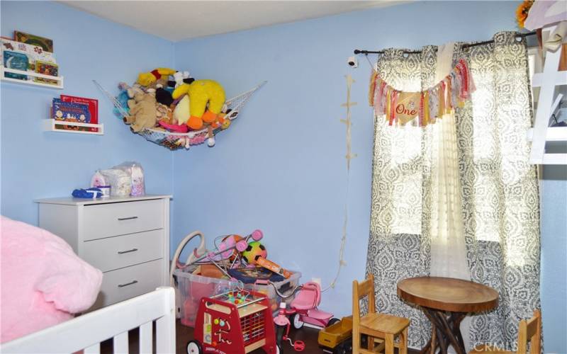 This darling 2nd bedroom offers more gorgeous wood laminate flooring, a modern ceiling fan, and views of the back patio.