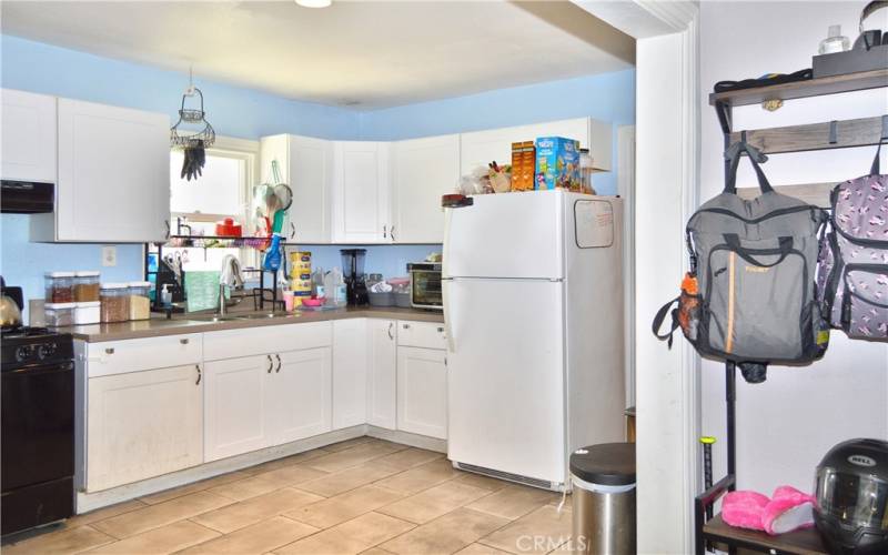 This attractive kitchen was fully remodeled in 2018 with porcelain tile flooring, modern Shaker-style cabinetry, quartz countertops, gas range, range hood, pull-out faucet, stainless steel double sinks and recessed lighting.