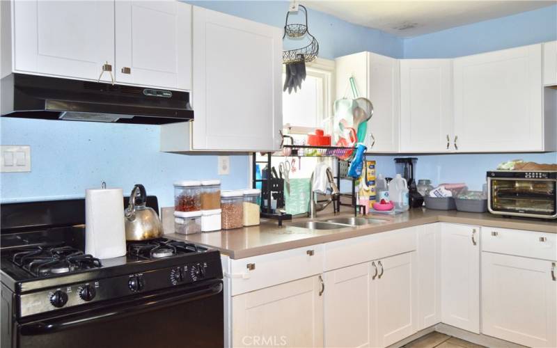 This attractive kitchen was fully remodeled in 2018 with porcelain tile flooring, modern Shaker-style cabinetry, quartz countertops, gas range, range hood, pull-out faucet, stainless steel double sinks and recessed lighting.