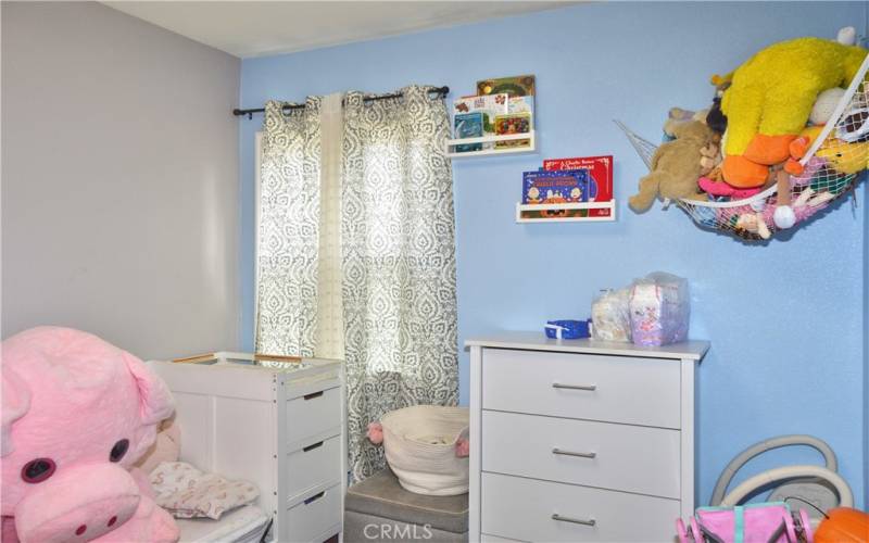 This darling 2nd bedroom offers more gorgeous wood laminate flooring, a modern ceiling fan, and views of the back patio.