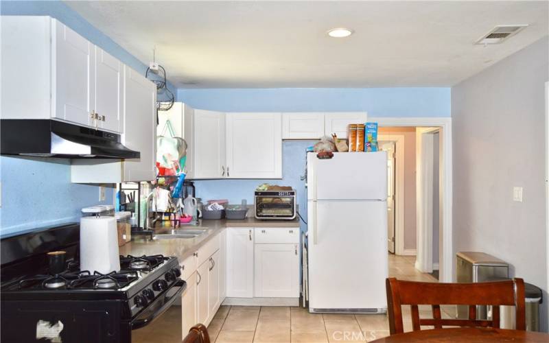 This attractive kitchen was fully remodeled in 2018 with porcelain tile flooring, modern Shaker-style cabinetry, quartz countertops, gas range, range hood, pull-out faucet, stainless steel double sinks and recessed lighting.