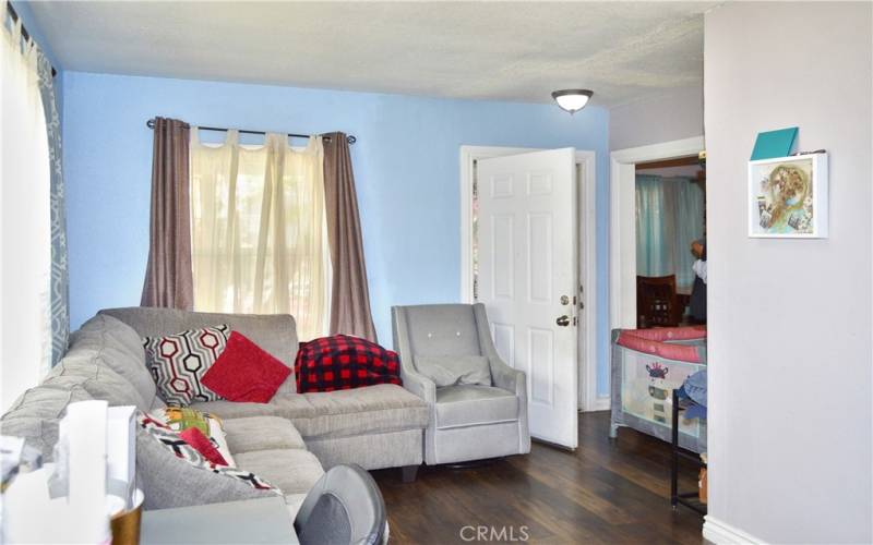 The spacious living room is at the front of the house with windows looking out on the front yard, gorgeous wood laminate flooring, and a modern ceiling fan light.