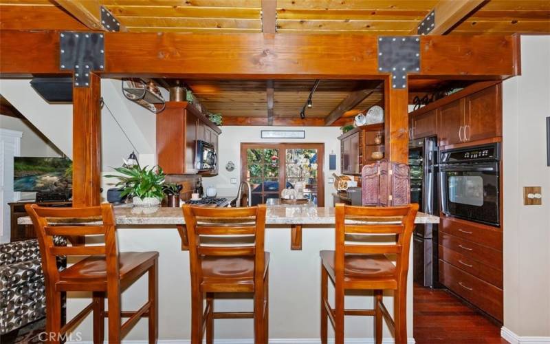 BREAKFAST BAR INTO KITCHEN, NOTICE WOOD FRAME FRENCH DOORS TO UPPER PATIO