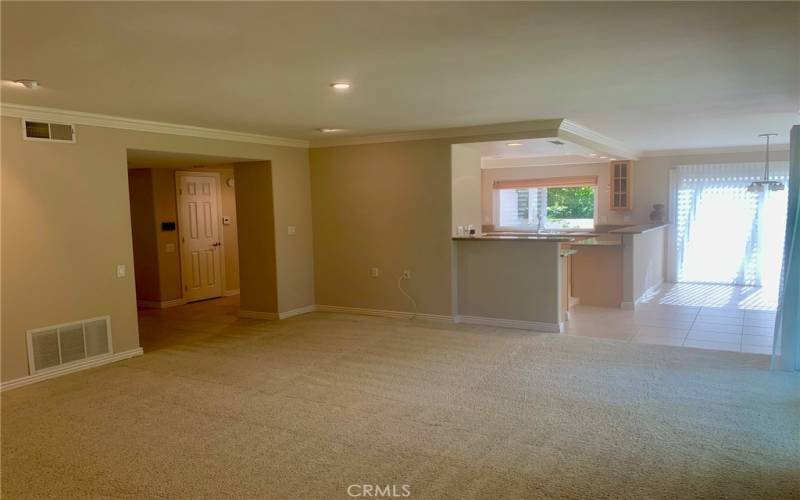 Another view of the living room looking towards the kitchen and dining area. Upgrades in this home include smooth ceilings, crown molding and baseboards, recessed lighting, dual-pane windows and many storage closets throughout.