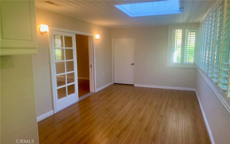 Another view of the bonus room just off the primary bedroom. Note the skylight and plantation shutters. The closed door at center opens to the garage.