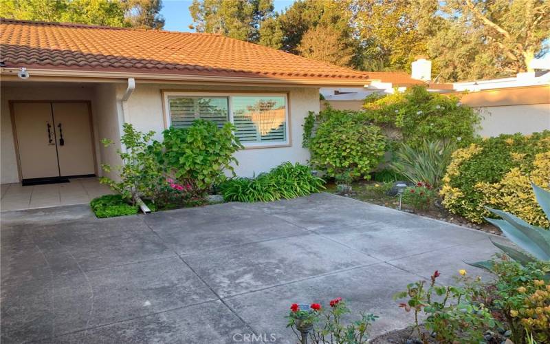 Large front courtyard surrounded by lush landscaping is the perfect spot for outdoor entertaining, dining and relaxing. Covered entry to residence can be seen at far left.