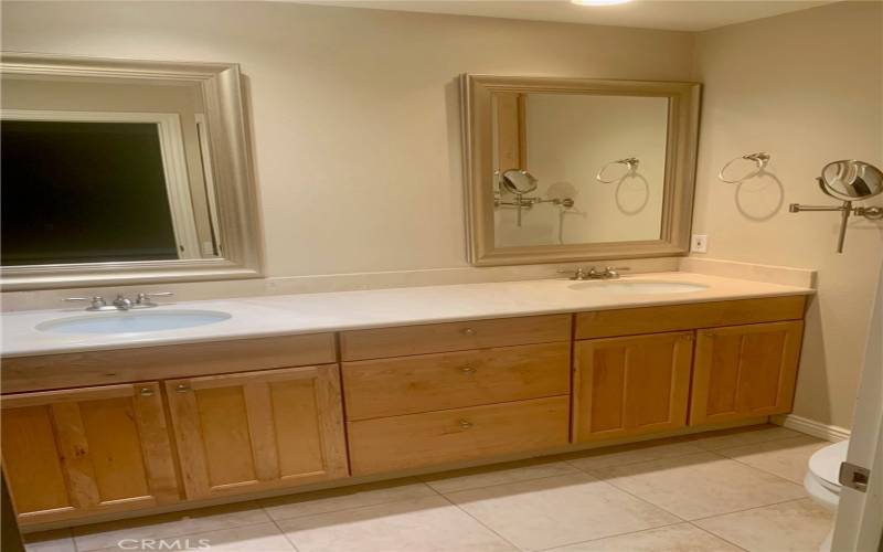 Primary bathroom has upgraded wood cabinetry and dual sinks.